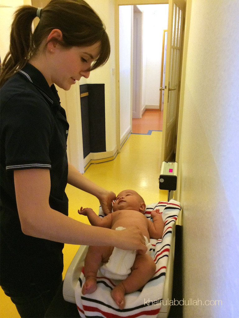 Khaleef sedang ditimbang berat oleh seorang nurse di klinik.